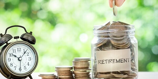 Hand putting Coins in glass jar with retro alarm clock , retirement Catching up on retirement
