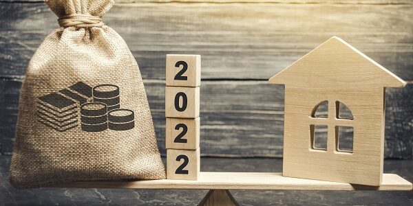 Money bag 2022 and a wooden house on the scales. Real estate concept. Family budget planning. Investments, plans, savings. Mortgage and mortgage rates. Forecasts. Loan. Refinance home 2022 Tax forecast