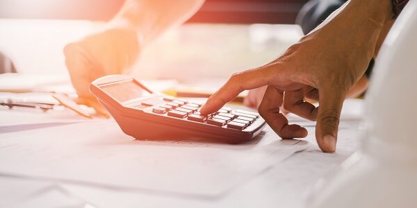 Close up man hand using calculator Calculating bonus(Or other compensation) to employees to increase productivity.Writing paper on desk.Selective Focus