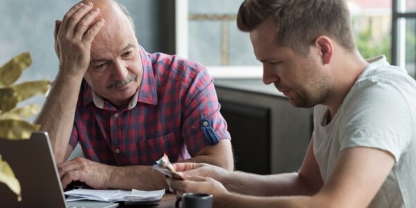 Elderly father and his adult son counting money. Have troubles with taxes and debts