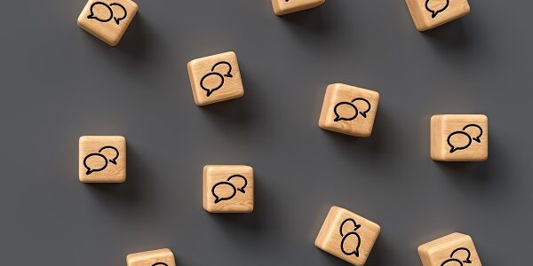 many cubes with speech bubble icons and smartphone on wooden bac