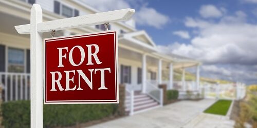 Red For Rent Real Estate Sign in Front of Beautiful House.