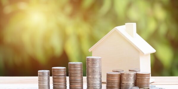 View Of coin stack with house model on green background, savings