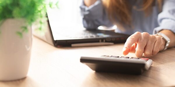 business woman hand with calculator and computer on desk